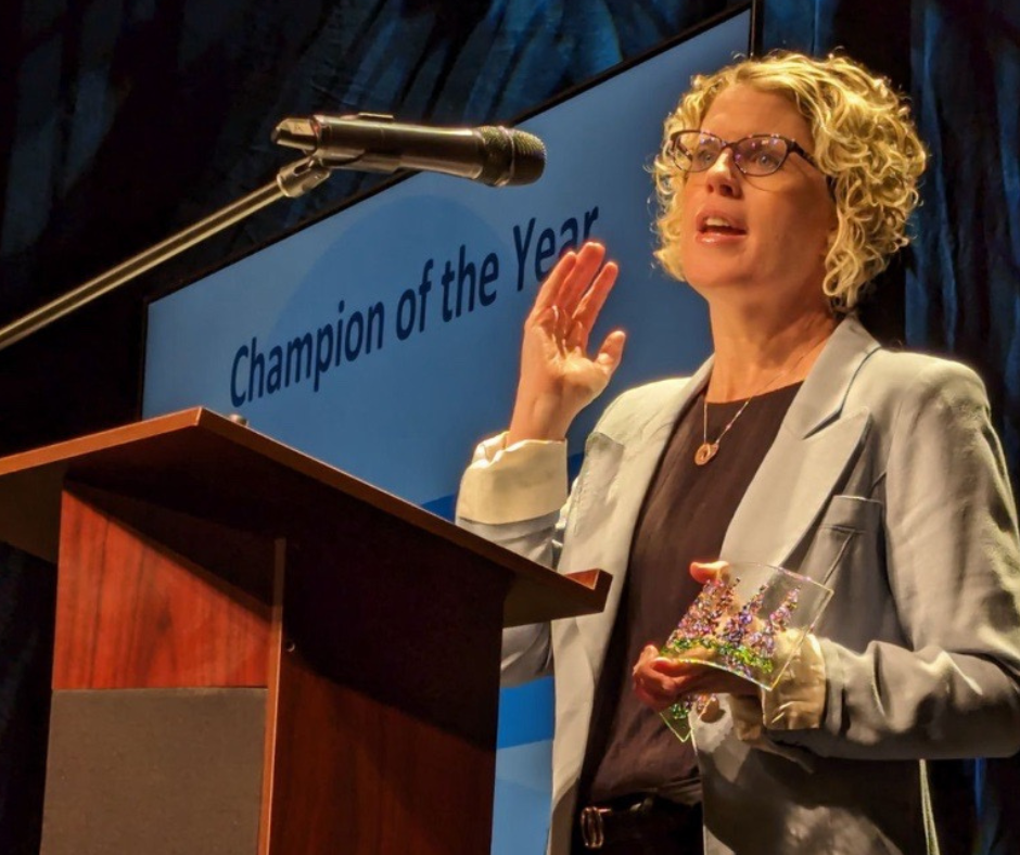 Suzanne stands at a podium giving remarks into a microphone