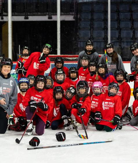 Cassie Campbell-Pascall and a group of hockey players pose on ice