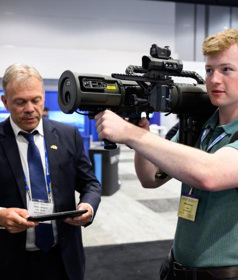 A delegate holds a rocket launcher in the DEFSEC exhibition room