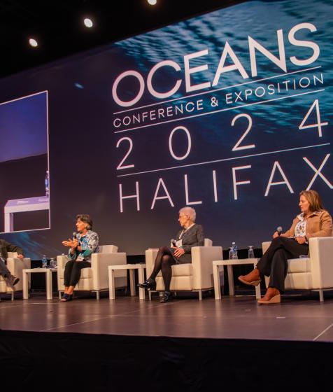 Panelists at OCEANS 2024 sit onstage in chairs 
