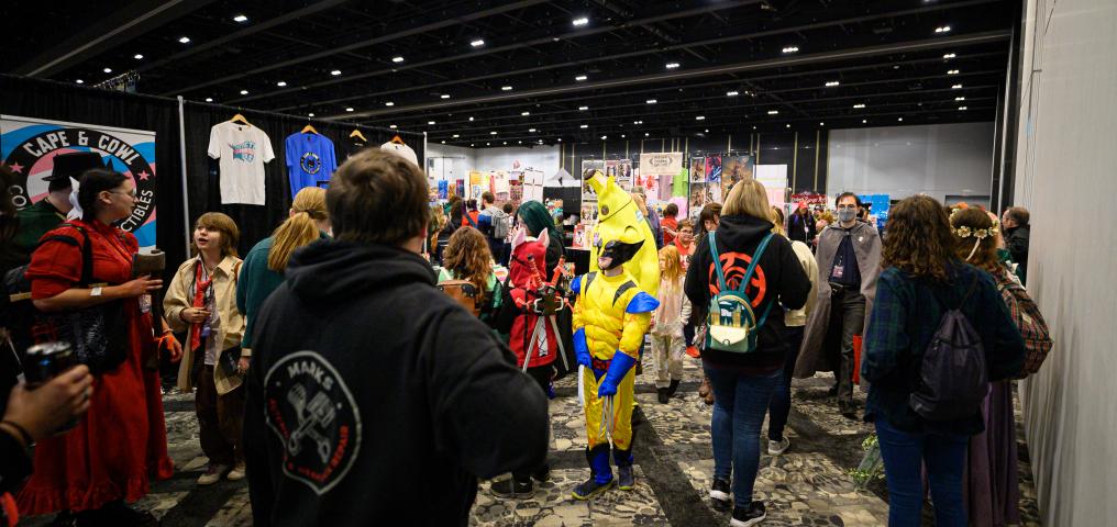 Vendor booths fill the room as a man in a Wolverine costume walks past the crowd