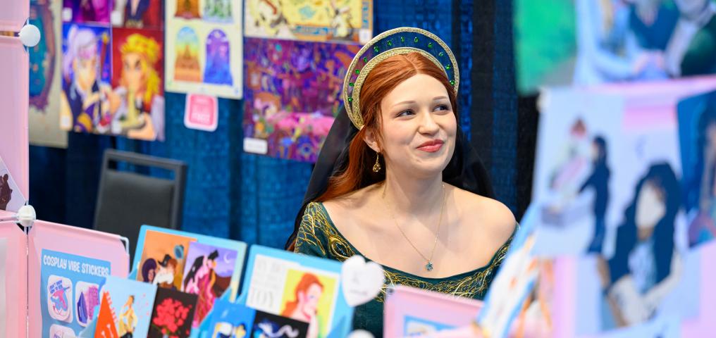 A vendor dressed in Renaissance costume sells her crafts at a booth 