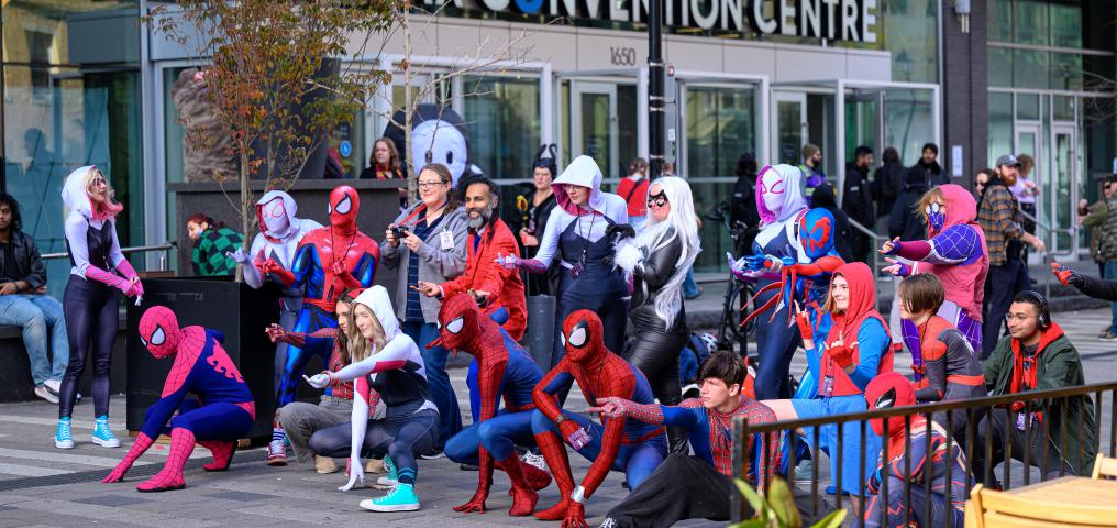 Many people in spiderman costumes pose outside of the Halifax Convention Centre