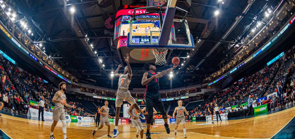 A fish-eye view of the basketball net, with players underneath scrambling for a ball