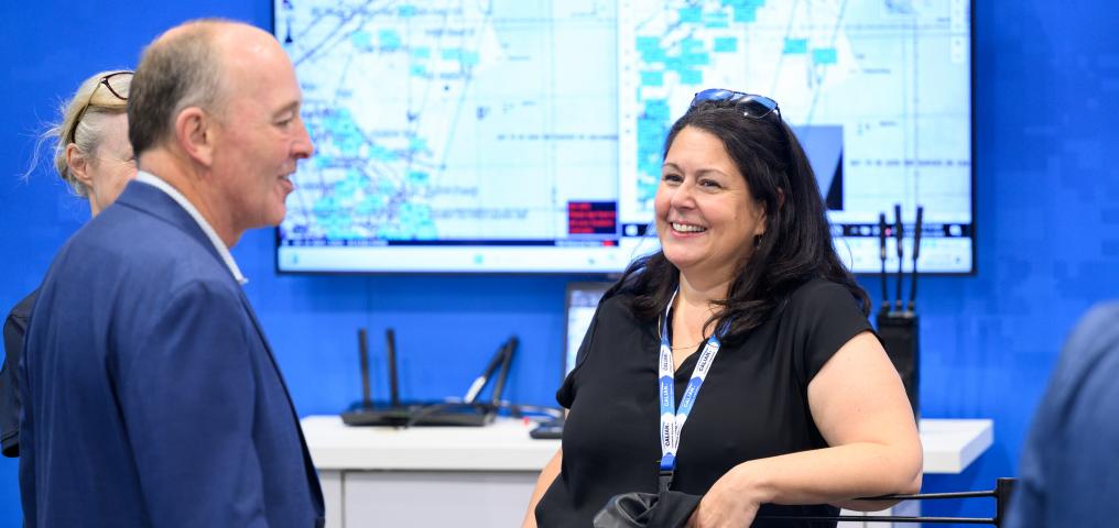 A woman smiles with her elbow resting on a trade show booth
